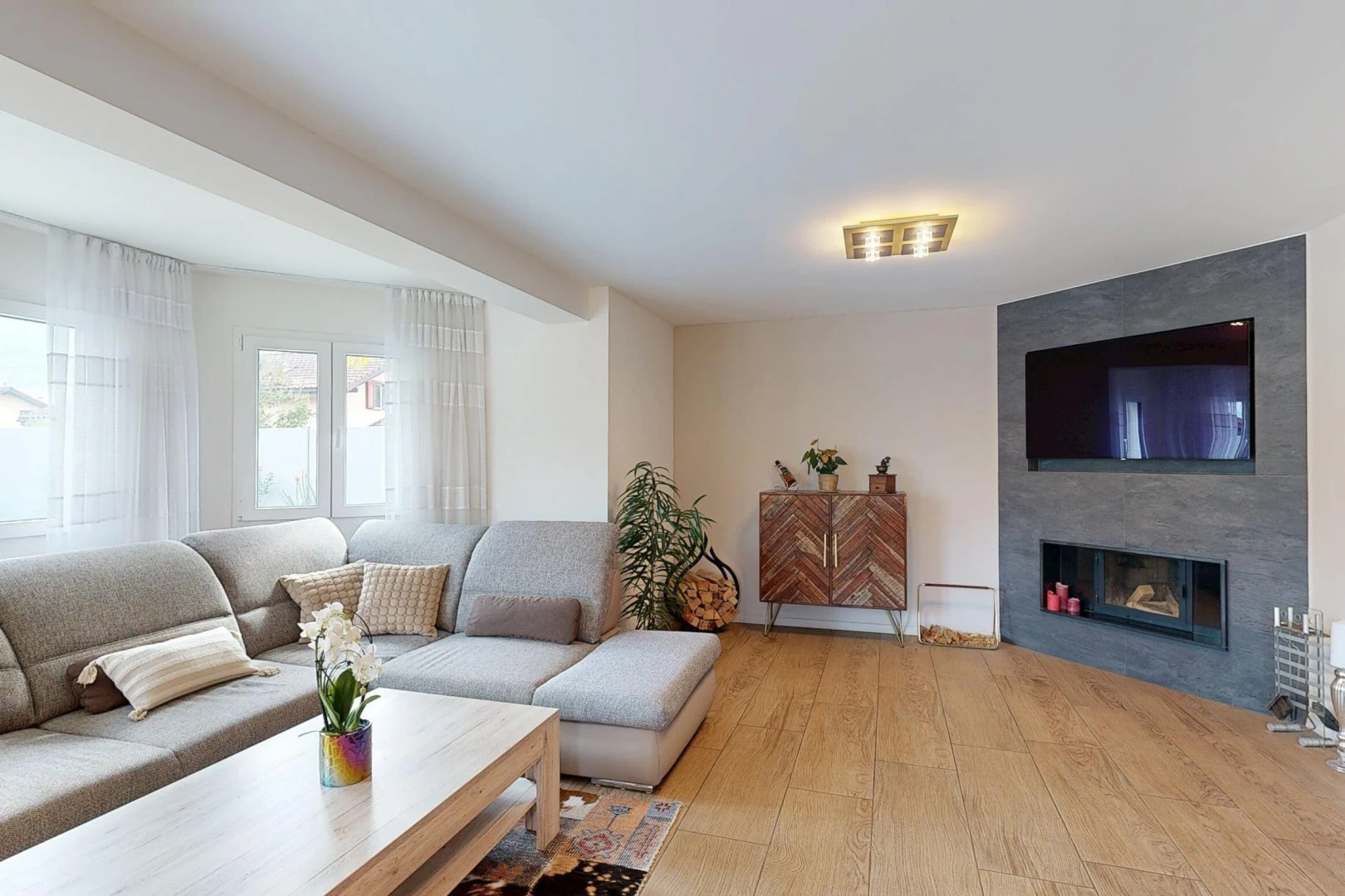 salon avec télévision, wood finish floor, sol en finition bois, cheminée, et drywall