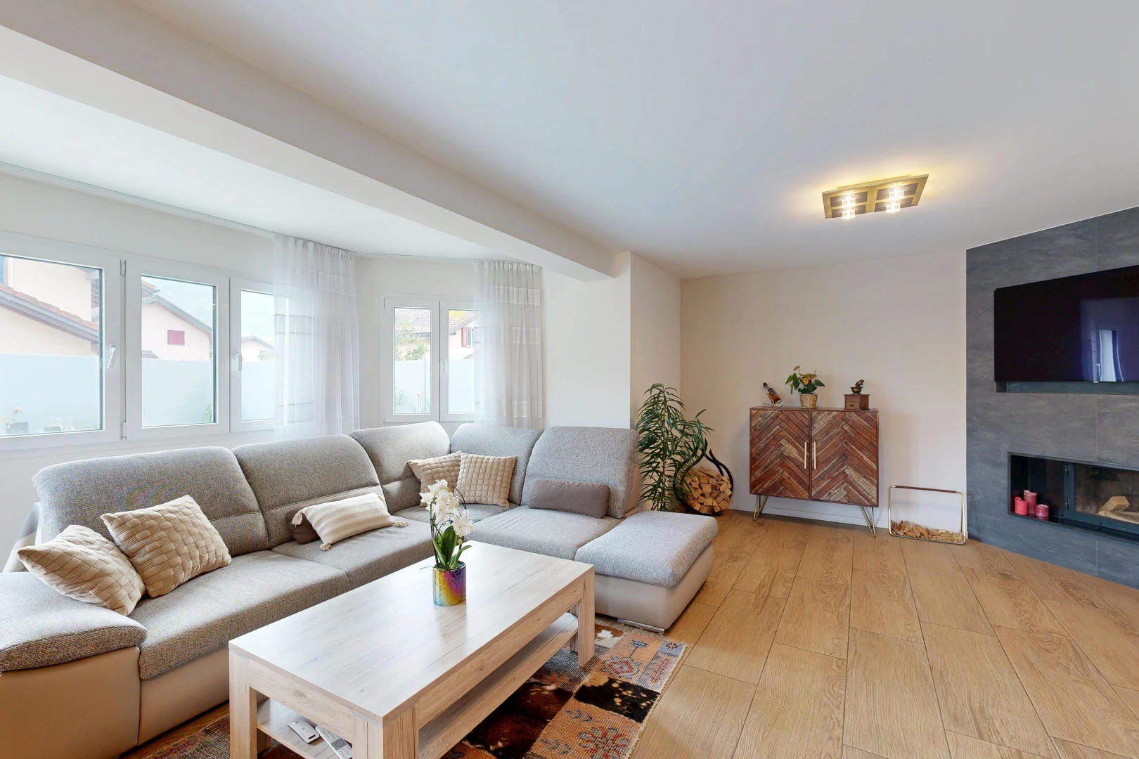 salon avec télévision, cheminée, wood finish floor, sol en finition bois, et light floor