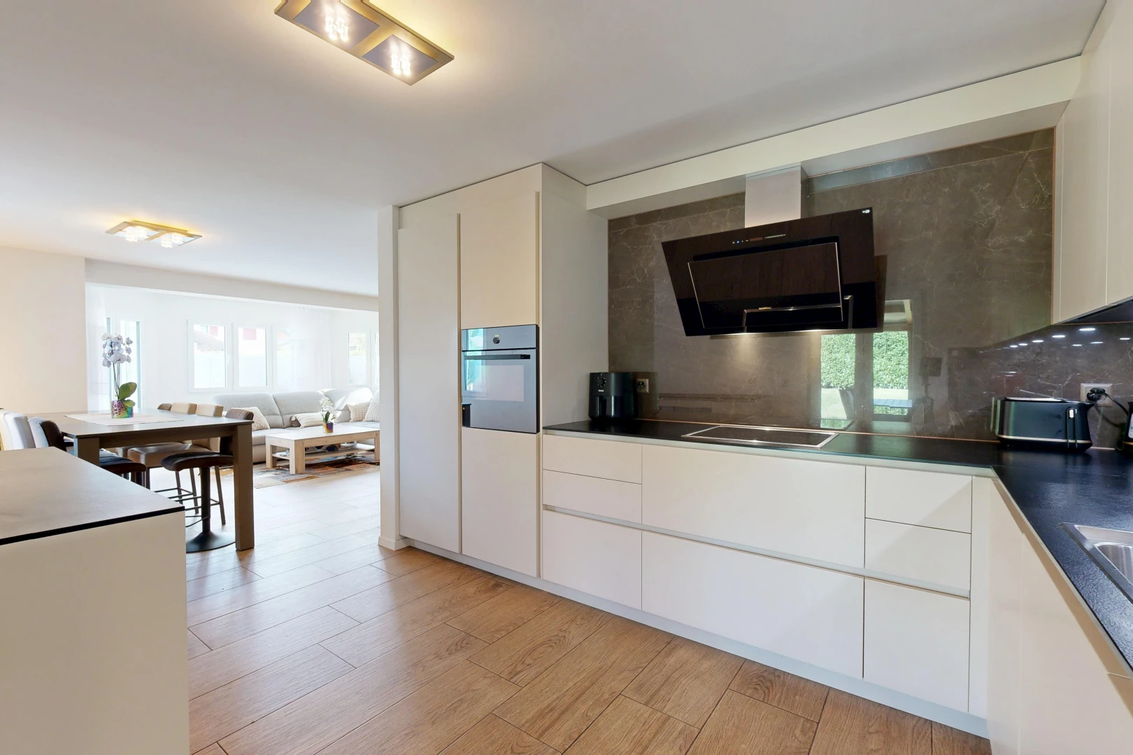 cuisine avec hotte, dark countertops, plans de travail, white cabinets, et armoires blanches