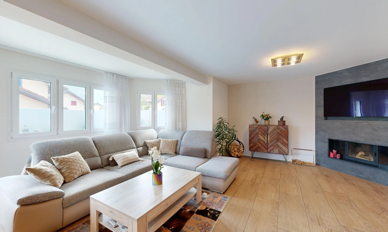 salon avec télévision, cheminée, wood finish floor, sol en finition bois, et light floor