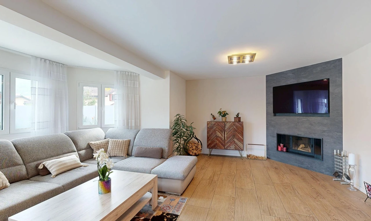 salon avec télévision, wood finish floor, sol en finition bois, cheminée, et drywall