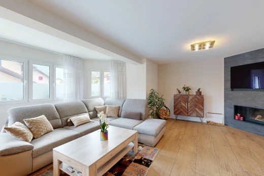 salon avec télévision, cheminée, wood finish floor, sol en finition bois, et light floor