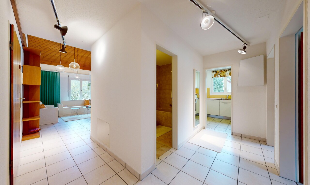 corridor featuring rail lighting, light tile patterned floors, and healthy amount of natural light