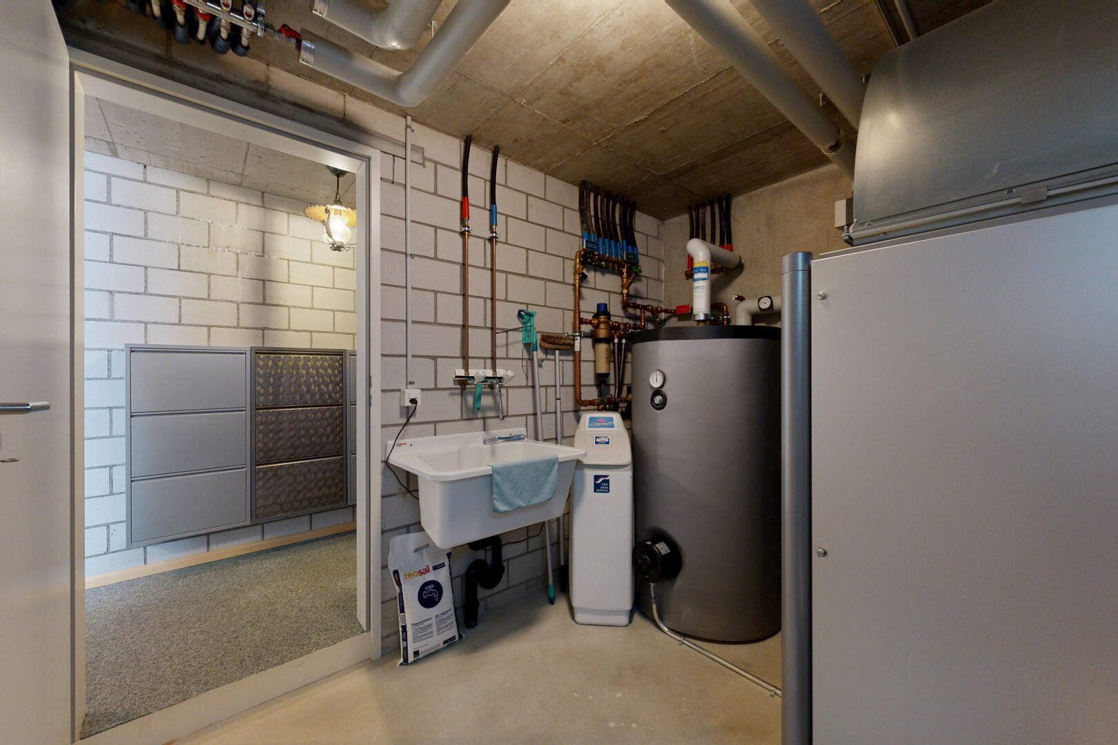cuisine avec inside community, chauffe-eau, light floor, concrete floor, et évier