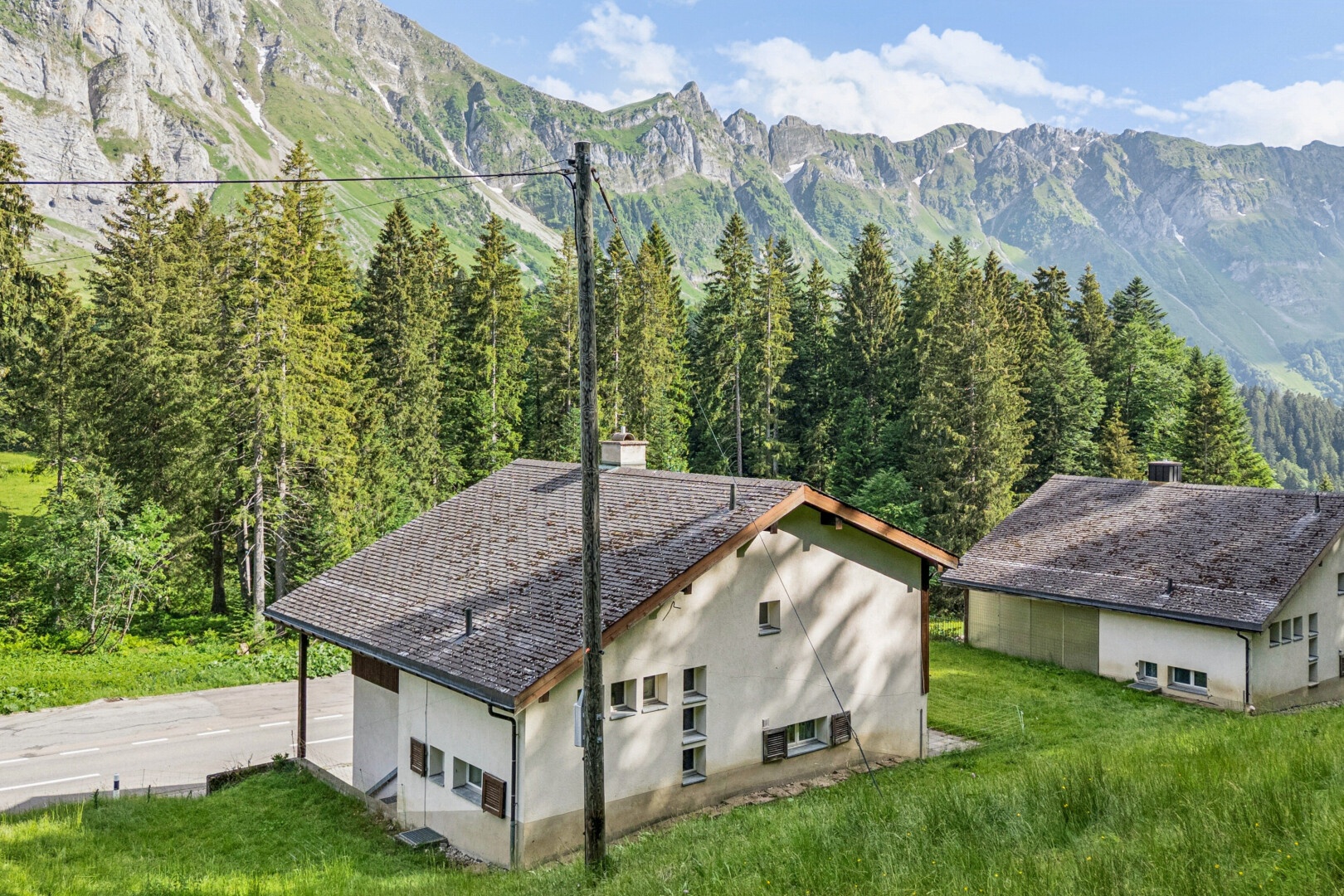 außenansicht mit stuckverkleidung, blick auf die berge, mountain view, rasen, und property visible