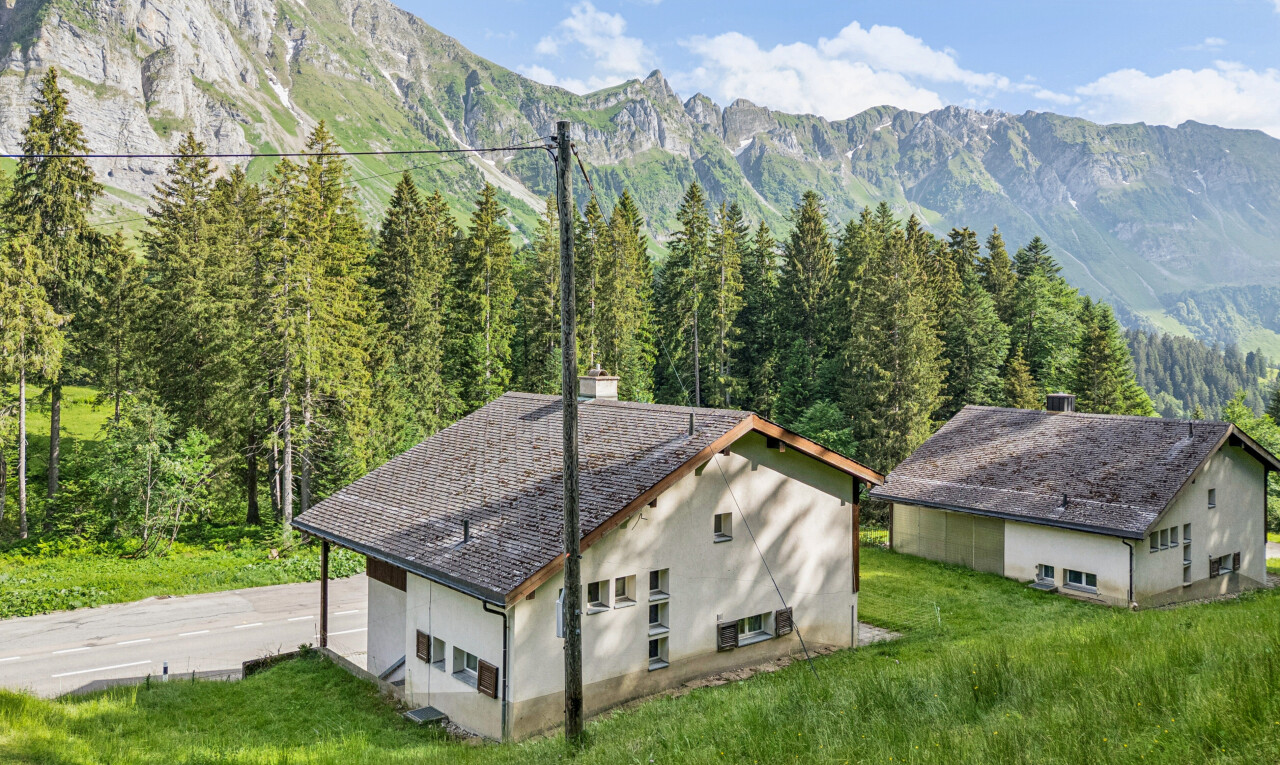 außenansicht mit stuckverkleidung, blick auf die berge, mountain view, rasen, und property visible