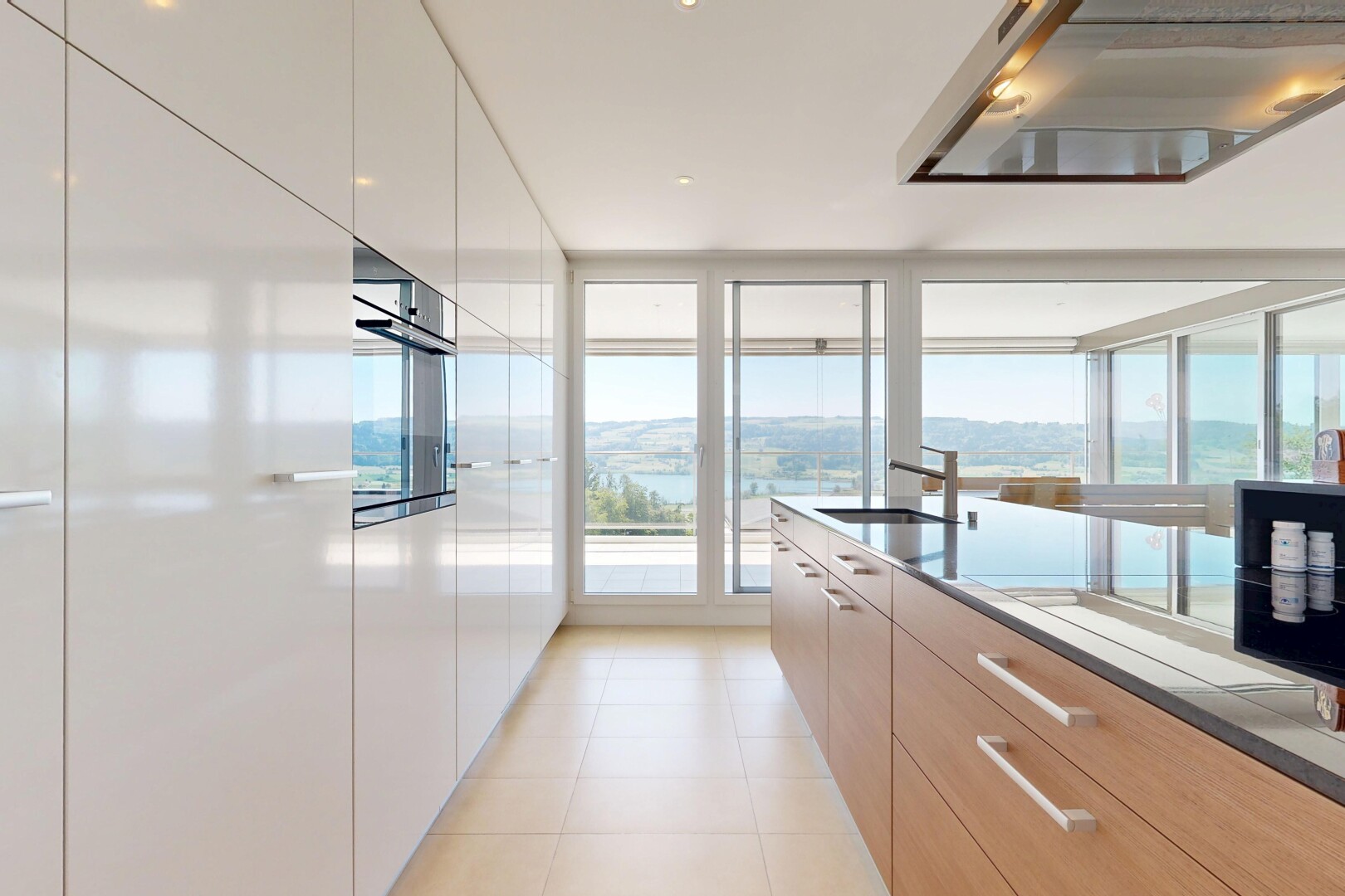 kitchen featuring ventilation hood, modern cabinets, oven, light tile patterned floors, and expansive windows