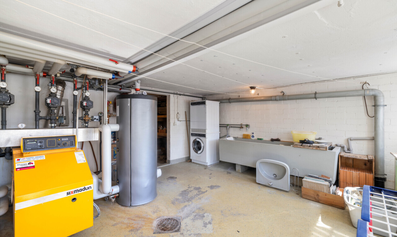 buanderie avec buanderie, chauffe-eau, inside property, chaudière, et sol en béton