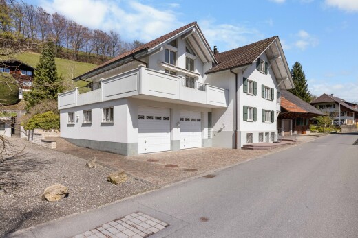 außenansicht mit eingebaute garage, stuckverkleidung, und day time