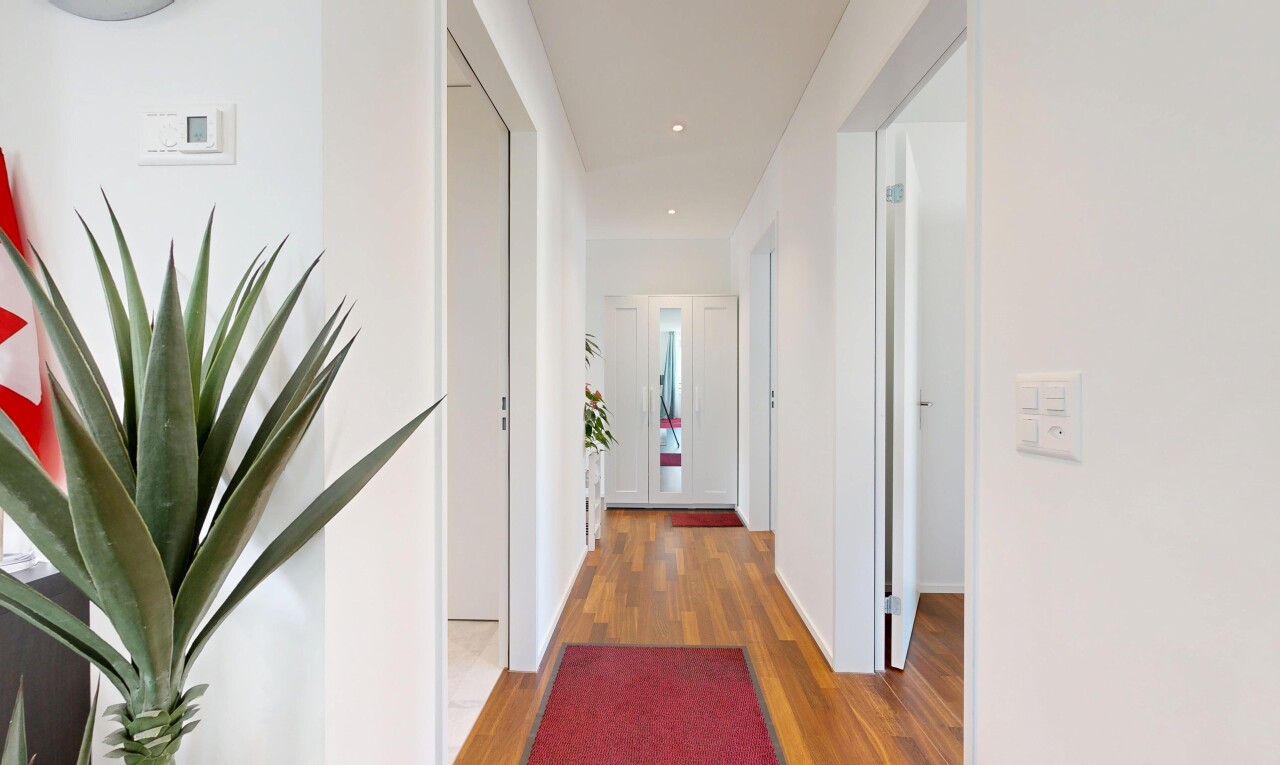 couloir avec cloison sèche, drywall, inside property, sol en finition bois, et wood finish floor