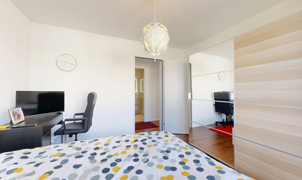 chambre avec espace bureau, télévision, placard, sol en finition bois, et wood finish floor