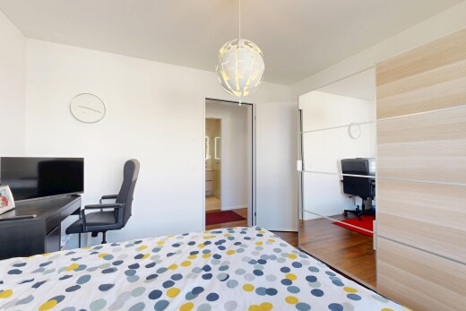 chambre avec espace bureau, télévision, placard, sol en finition bois, et wood finish floor