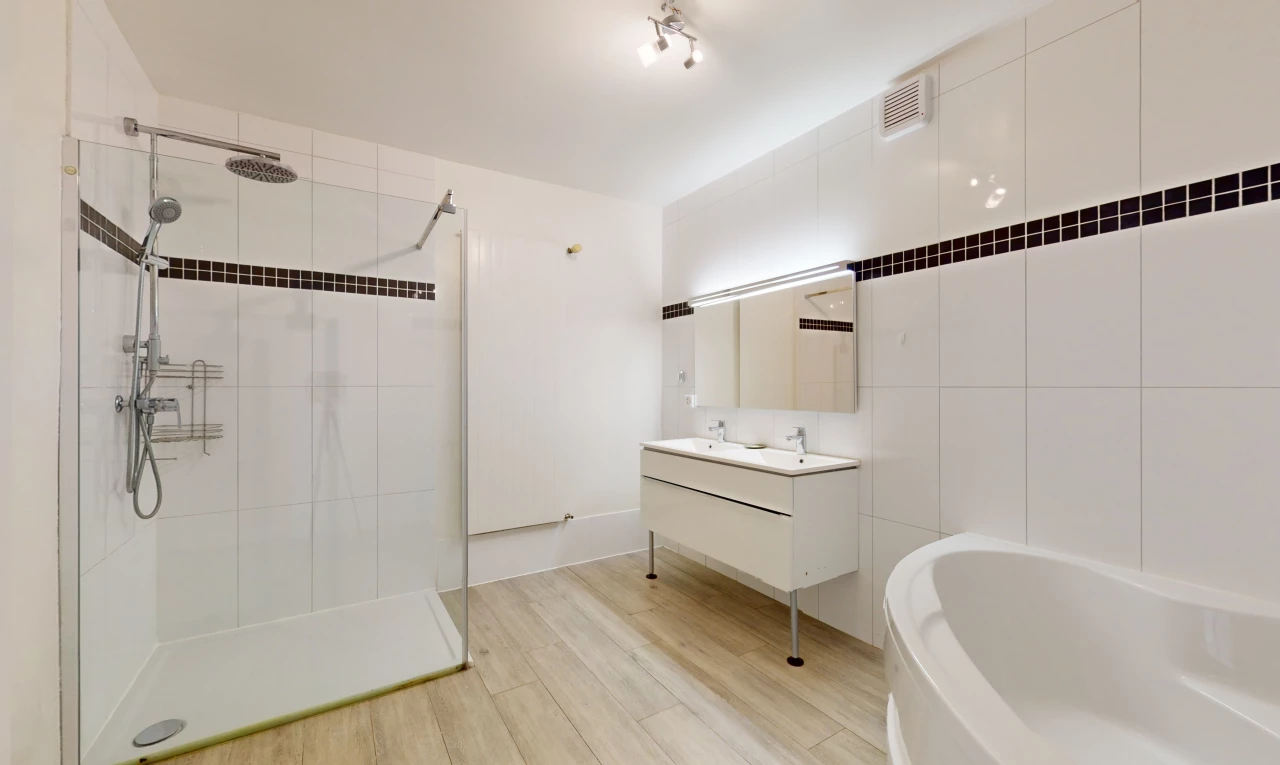 salle de bain avec meuble-lavabo, douche, plancher de bois, vasque, et mur carrelé
