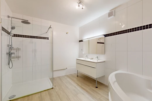 salle de bain avec meuble-lavabo, douche, plancher de bois, vasque, et mur carrelé