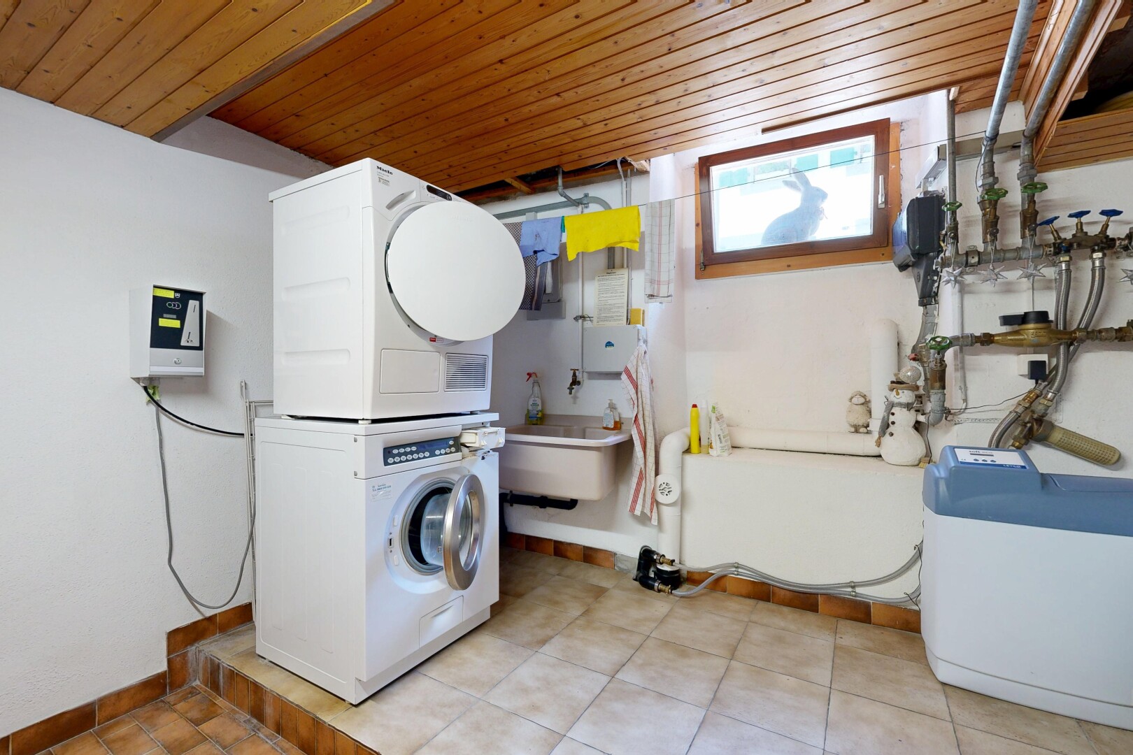 laundry area featuring stacked washer / drying machine and wood ceiling