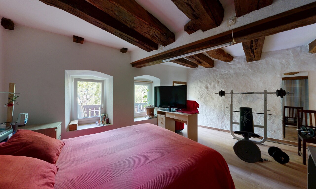 room / bedroom with beam ceiling, a barn door, and wood finished floors