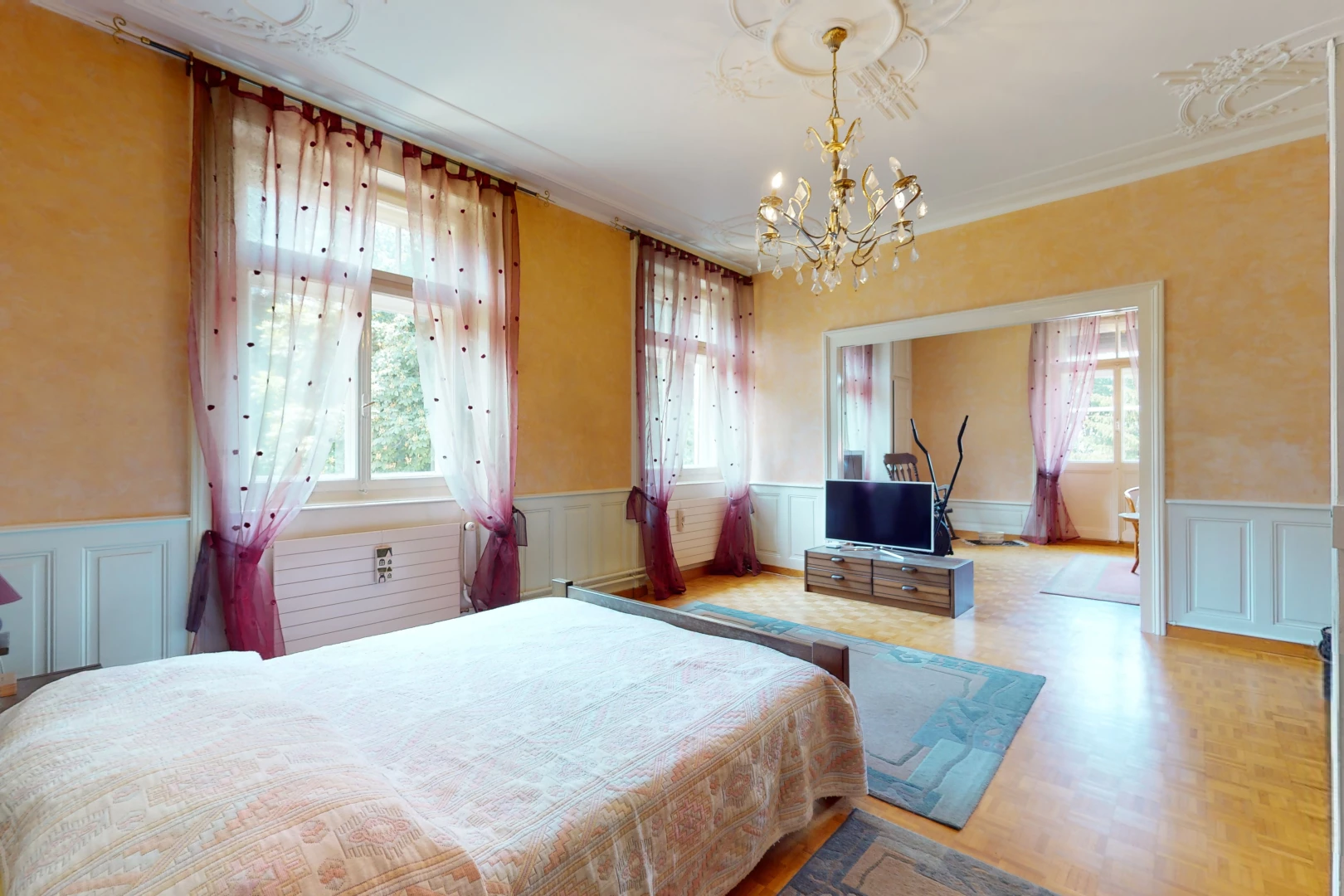 bedroom with hardwood floors, multiple windows, a chandelier, and TV