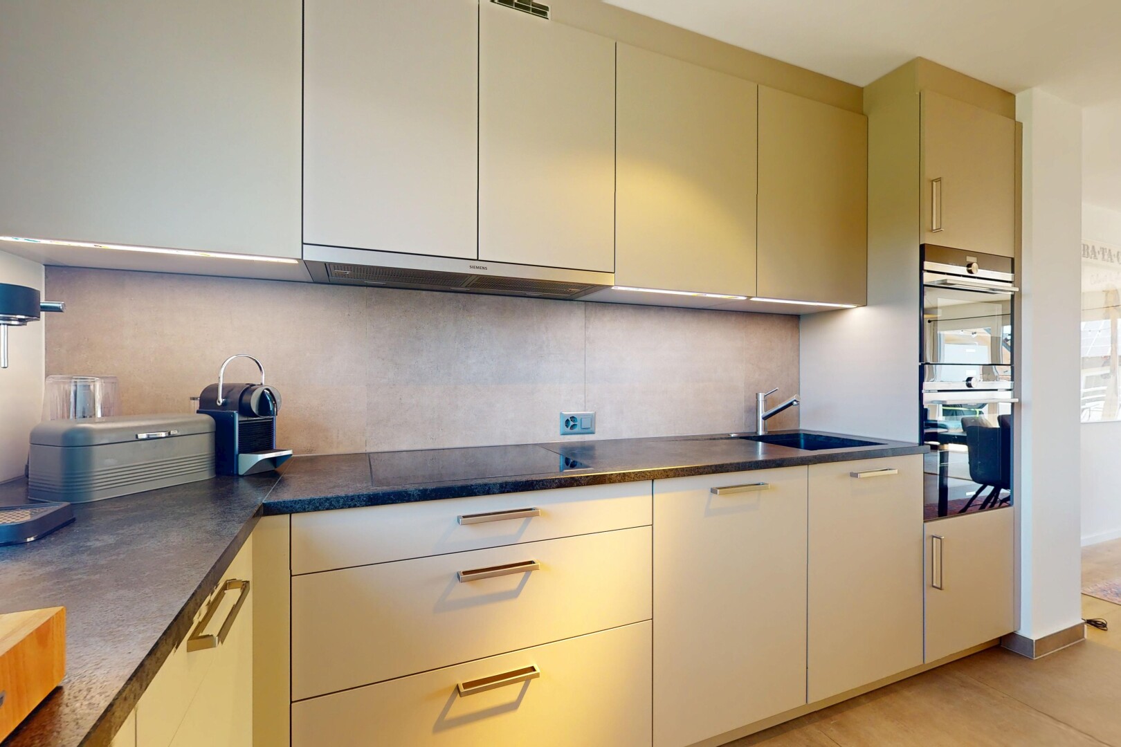 kitchen featuring stainless steel double oven, range hood, backsplash, and dark countertops