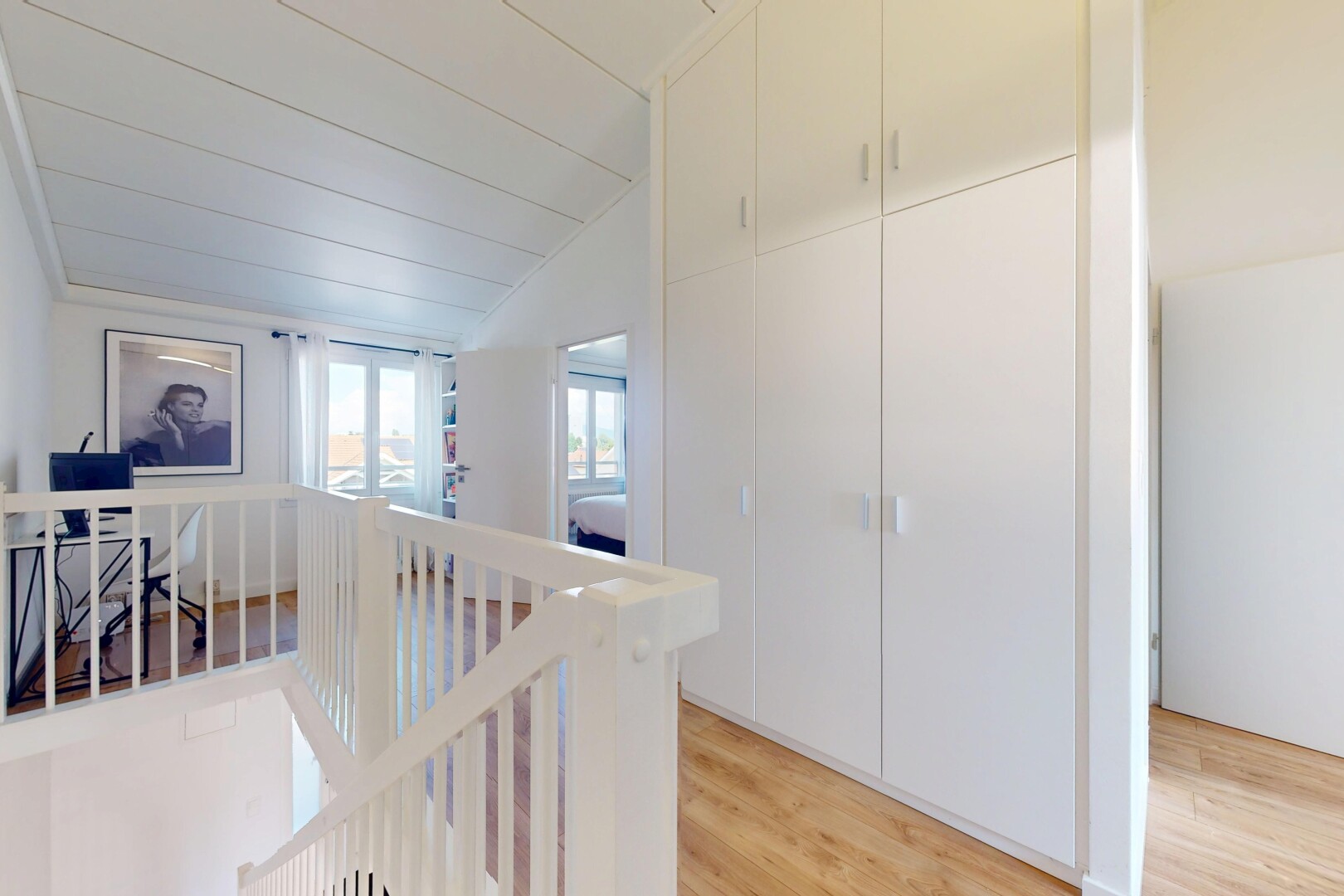 corridor with an upstairs landing, light wood-style flooring, and lofted ceiling