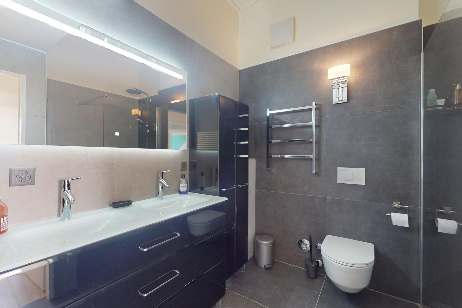 bathroom with tile walls, tile patterned flooring, a towel warmer, double vanity, and radiator