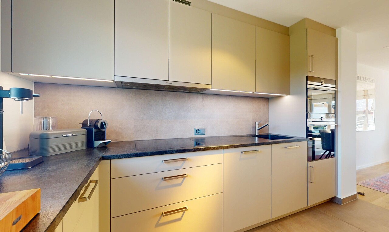 kitchen featuring stainless steel double oven, range hood, backsplash, and dark countertops