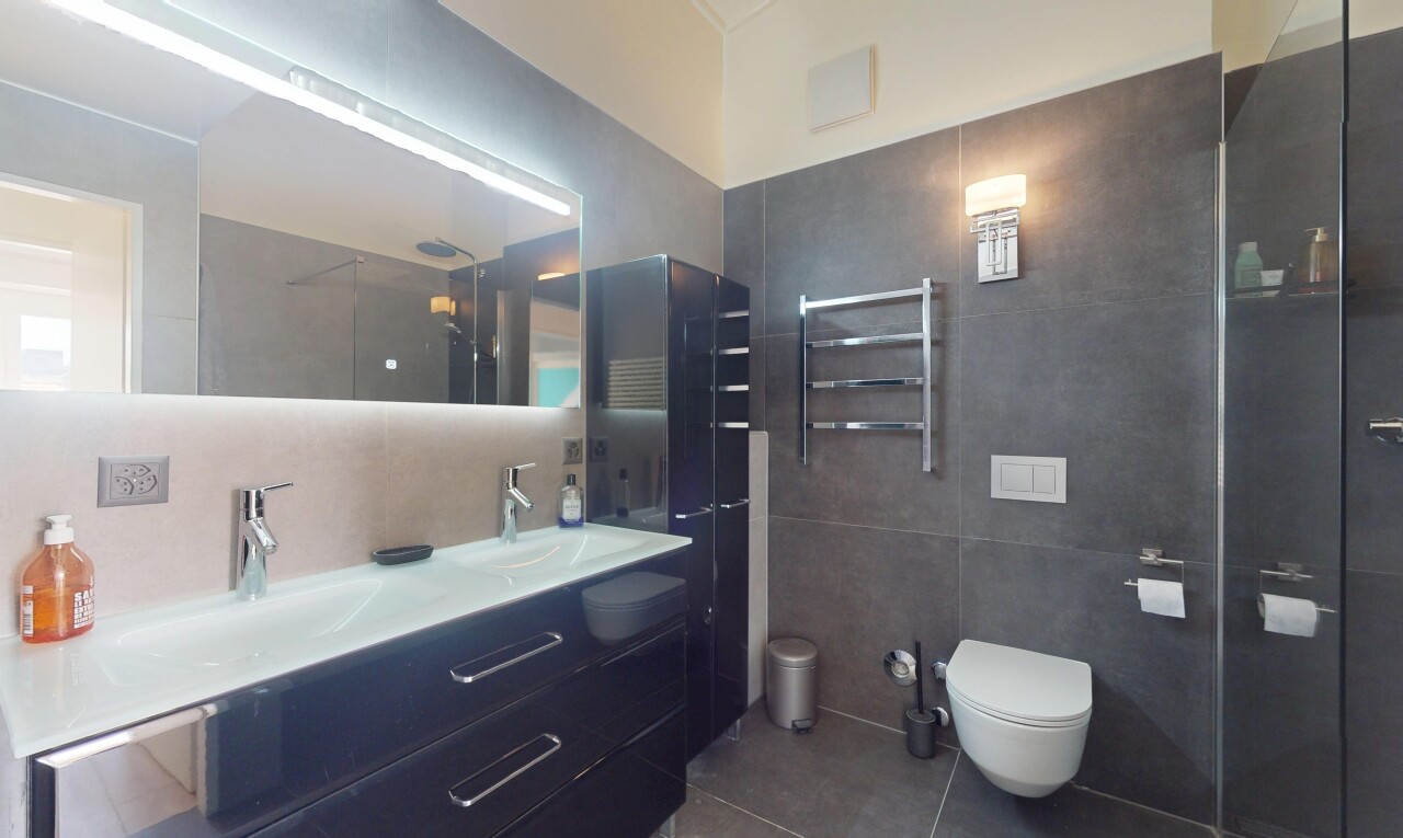 bathroom with tile walls, tile patterned flooring, a towel warmer, double vanity, and radiator