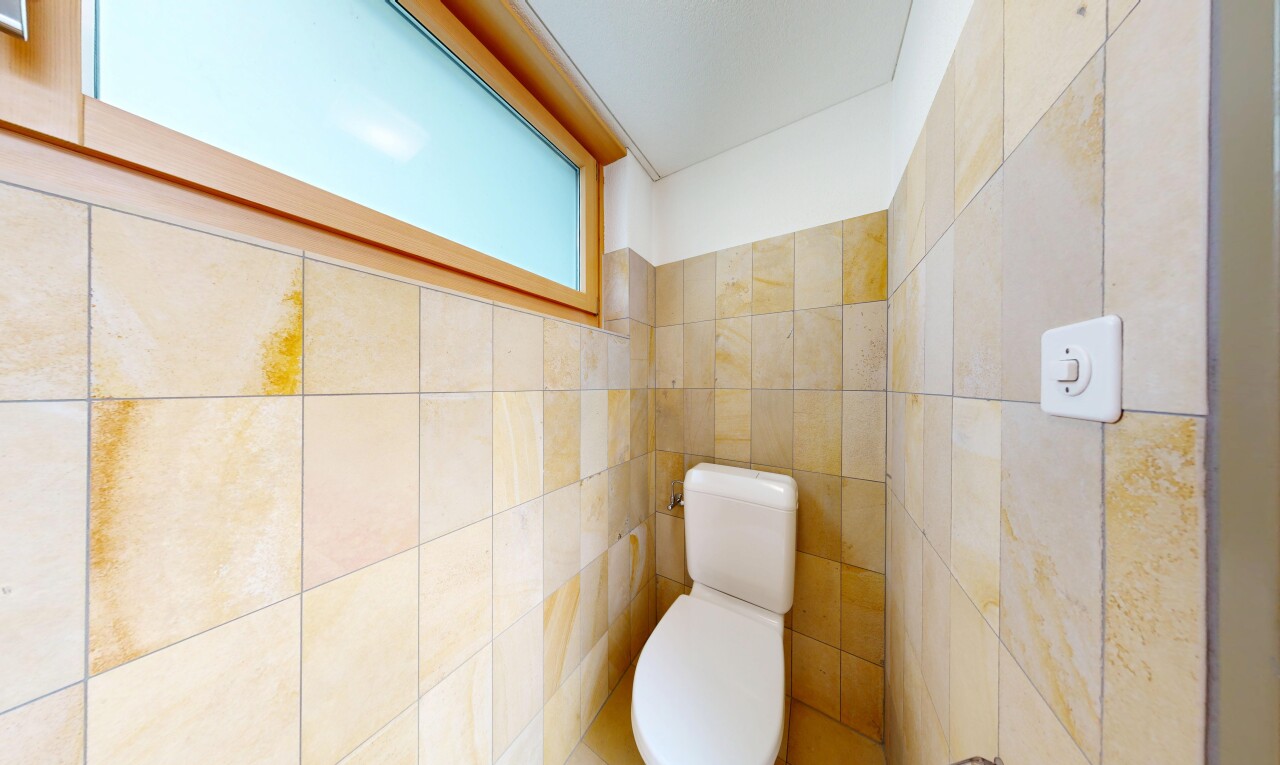 half bathroom with toilet and tile walls