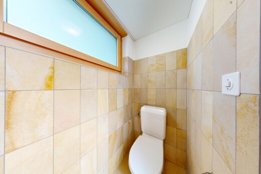 half bathroom with toilet and tile walls