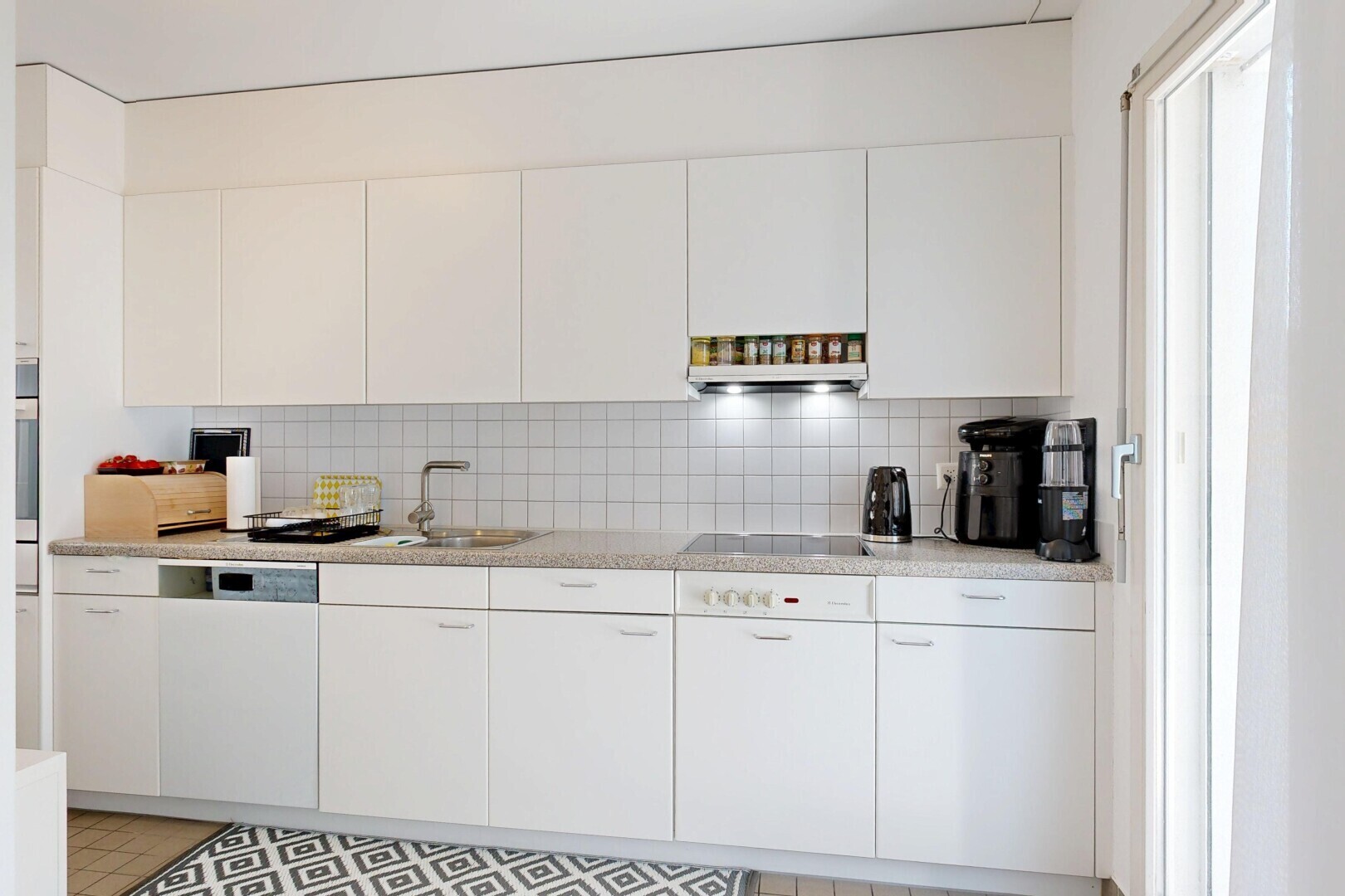 cuisine avec light countertops, backsplash, dosseret, light floor, et white cabinets