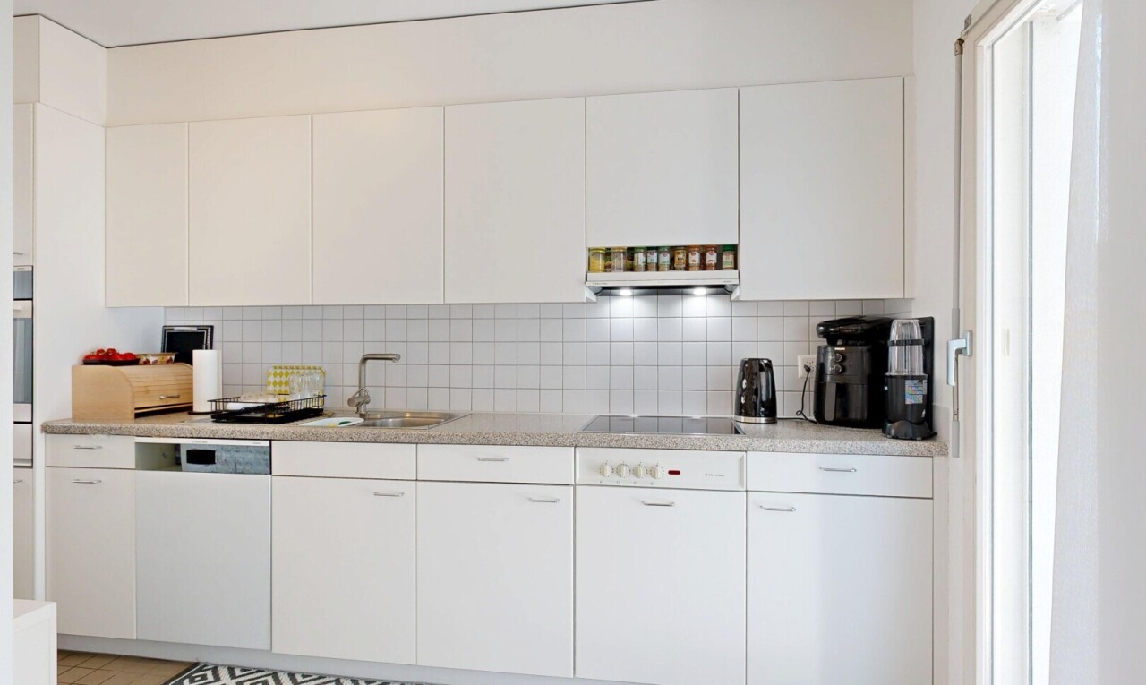 cuisine avec light countertops, backsplash, dosseret, light floor, et white cabinets