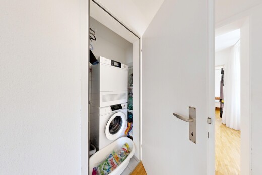 laundry area with stacked washer / drying machine and light wood-style floors