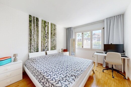 chambre avec drywall, cloison sèche, télévision, espace bureau, et wood finish floor