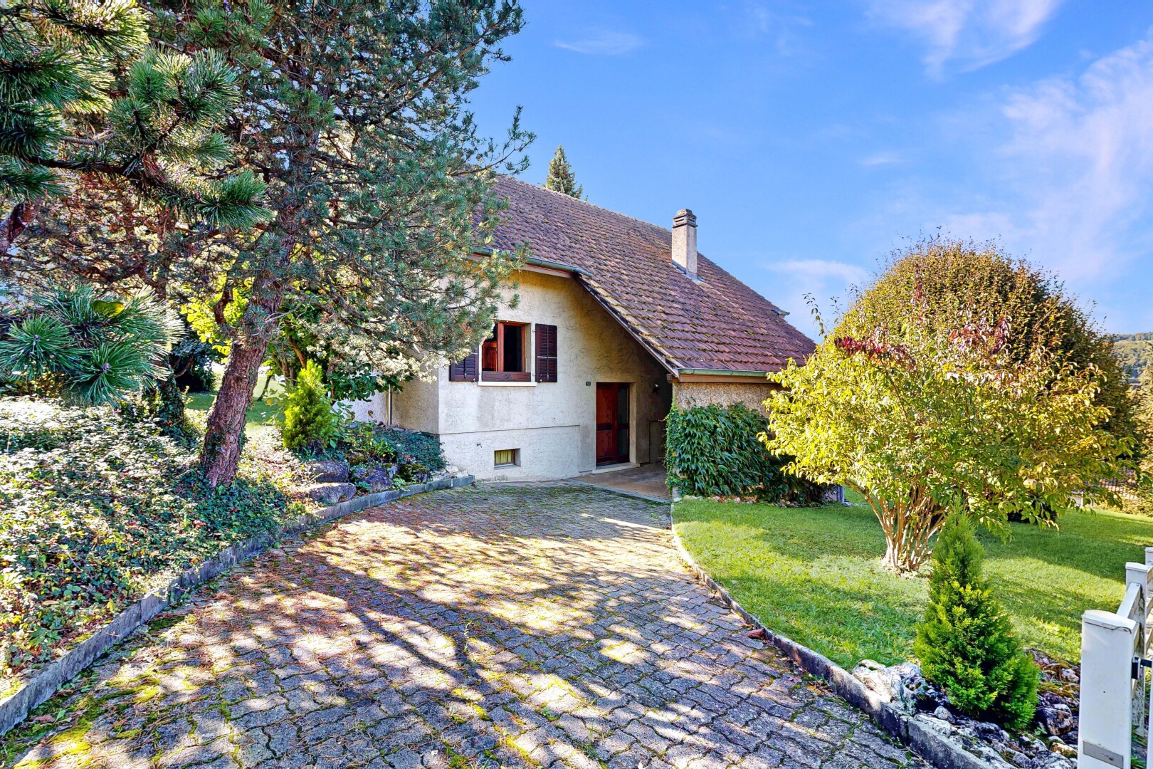 façade avec property visible, pelouse, cheminée, bardage en stuc, et day time