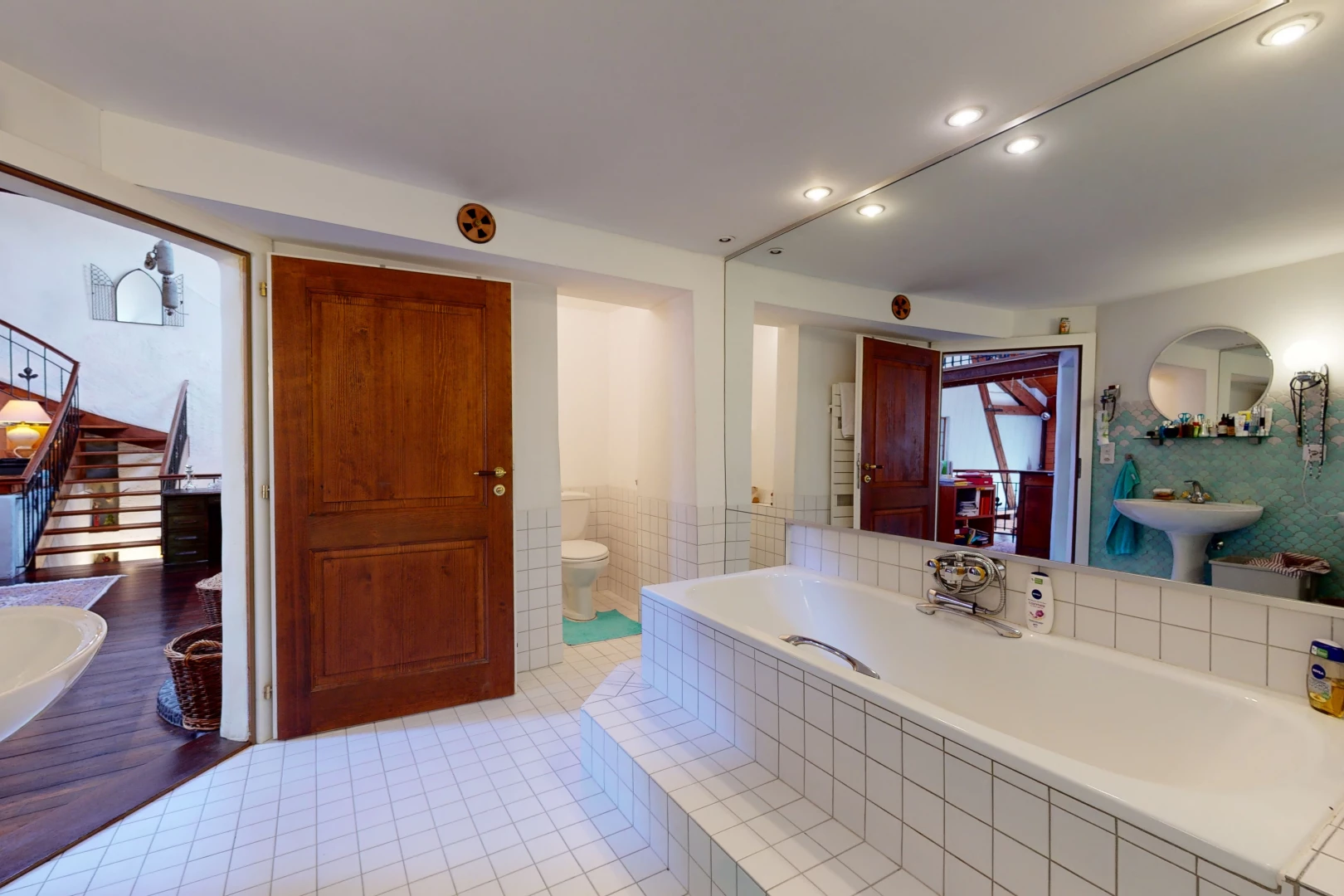 salle de bains avec carrelage, toilette, miroir, et baignoire