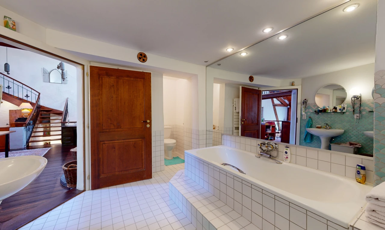 salle de bains avec carrelage, toilette, miroir, et baignoire