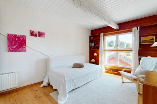 chambre à coucher avec parquet, lumière naturelle, poutres apparentes, et radiateur