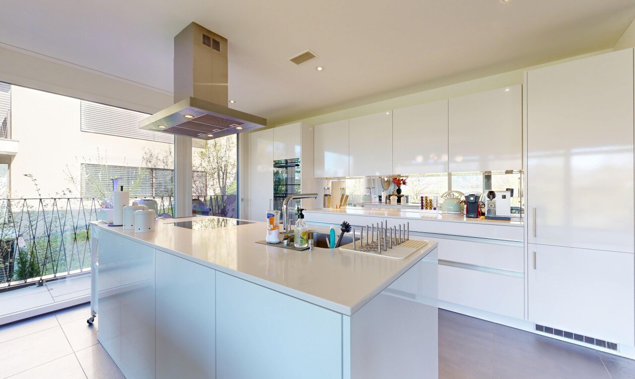 cuisine avec hotte, armoires à panneau plat, flat panel cabinets, light countertops, et îlot de cuisine
