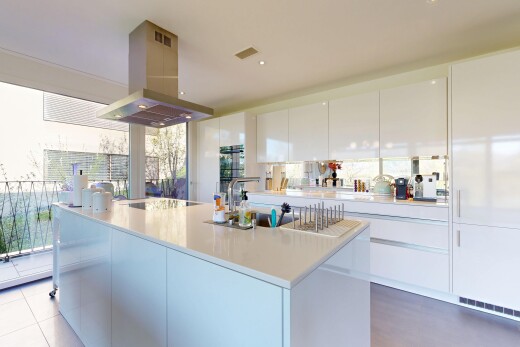 cuisine avec hotte, armoires à panneau plat, flat panel cabinets, light countertops, et îlot de cuisine