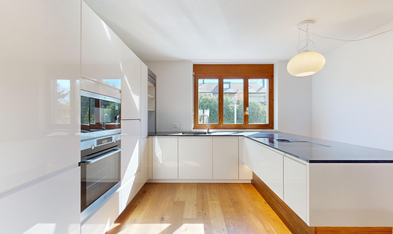 cuisine avec four, armoires à panneau plat, flat panel cabinets, dark countertops, et sol en finition bois