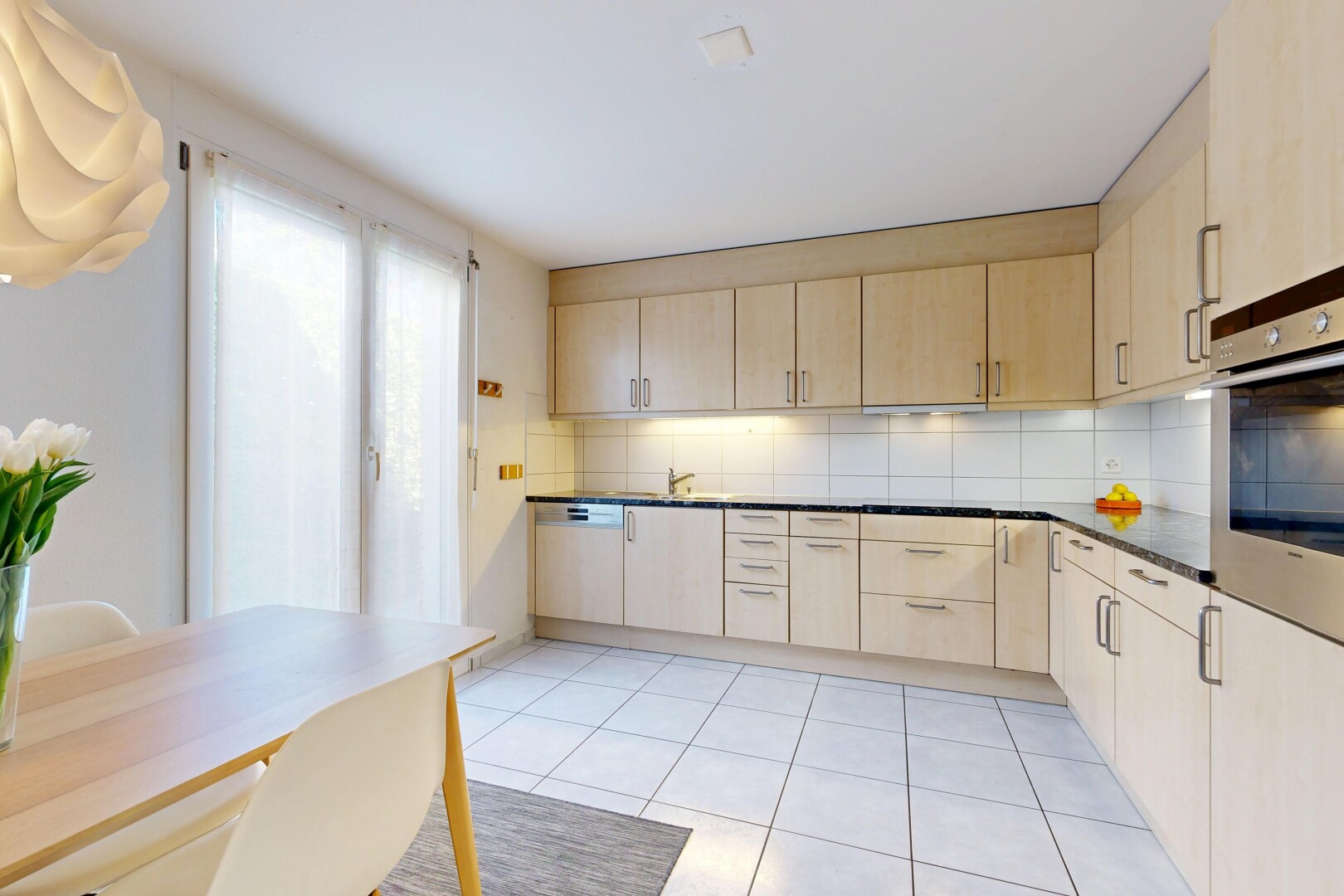 kitchen with light wood finish cabinets, oven, backsplash, and light tile patterned floors