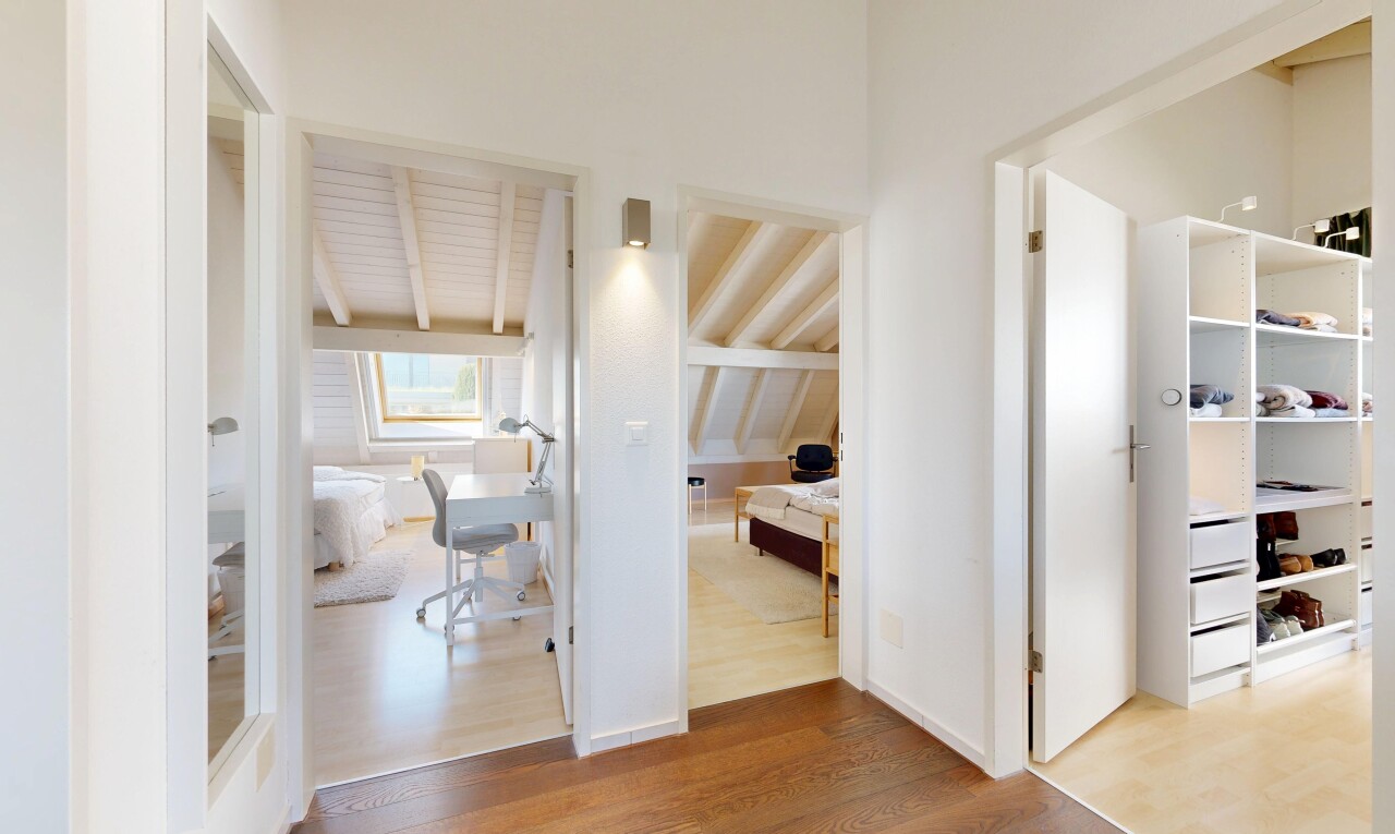 hallway with an office area, light wood-style flooring, and beam ceiling
