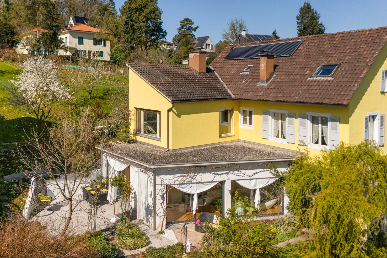 façade avec bardage en stuc, panneaux solaires, cheminée, et toit en bardeaux