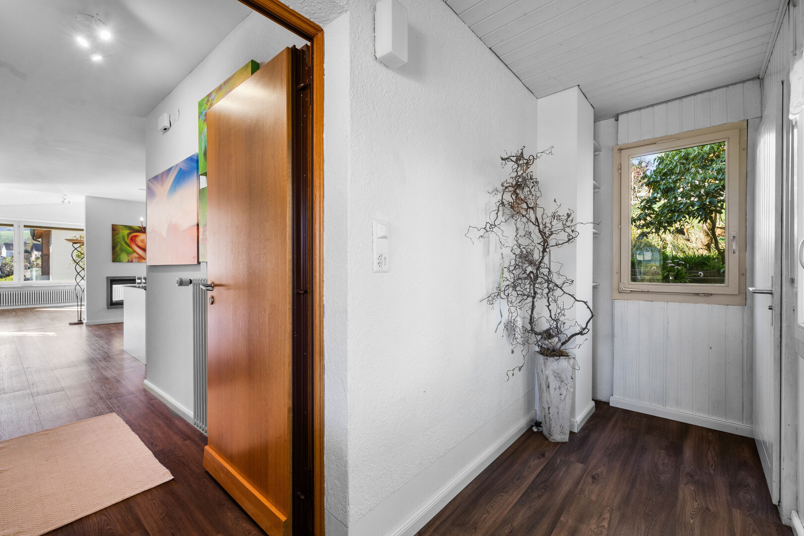 couloir avec lumière naturelle, sol en finition bois, et plinthes murales