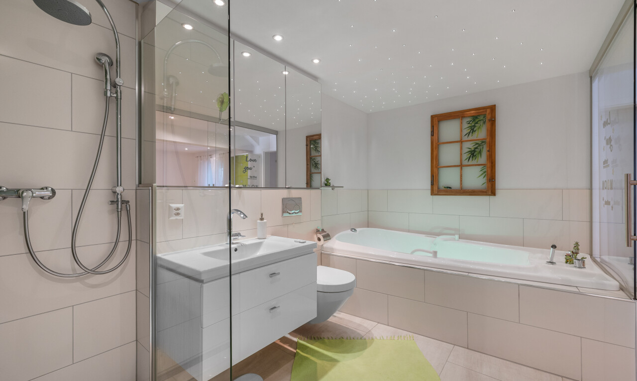 salle de bains avec lavabo (ou coiffeuse selon le contexte), évier, bain, mur en carrelage, et toilette
