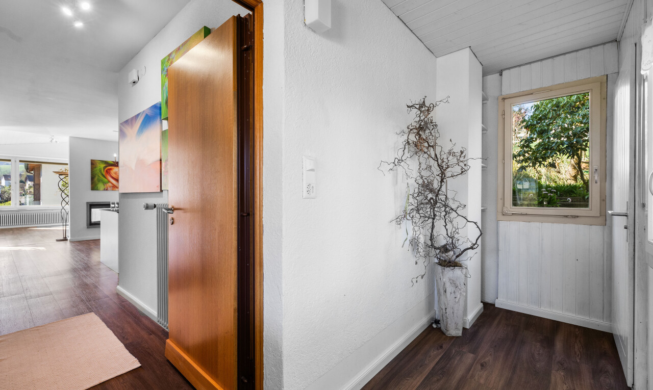 couloir avec lumière naturelle, sol en finition bois, et plinthes murales