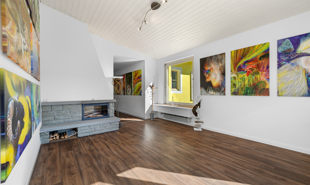 salon avec sol en finition bois, cheminée, plinthes murales, cloison sèche, et plafond voûté