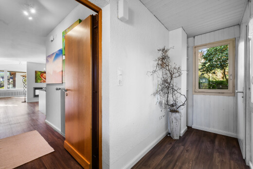 couloir avec lumière naturelle, sol en finition bois, et plinthes murales
