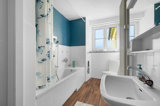 salle de bains avec sol en finition bois, évier, lumière naturelle, et salle de bain complète