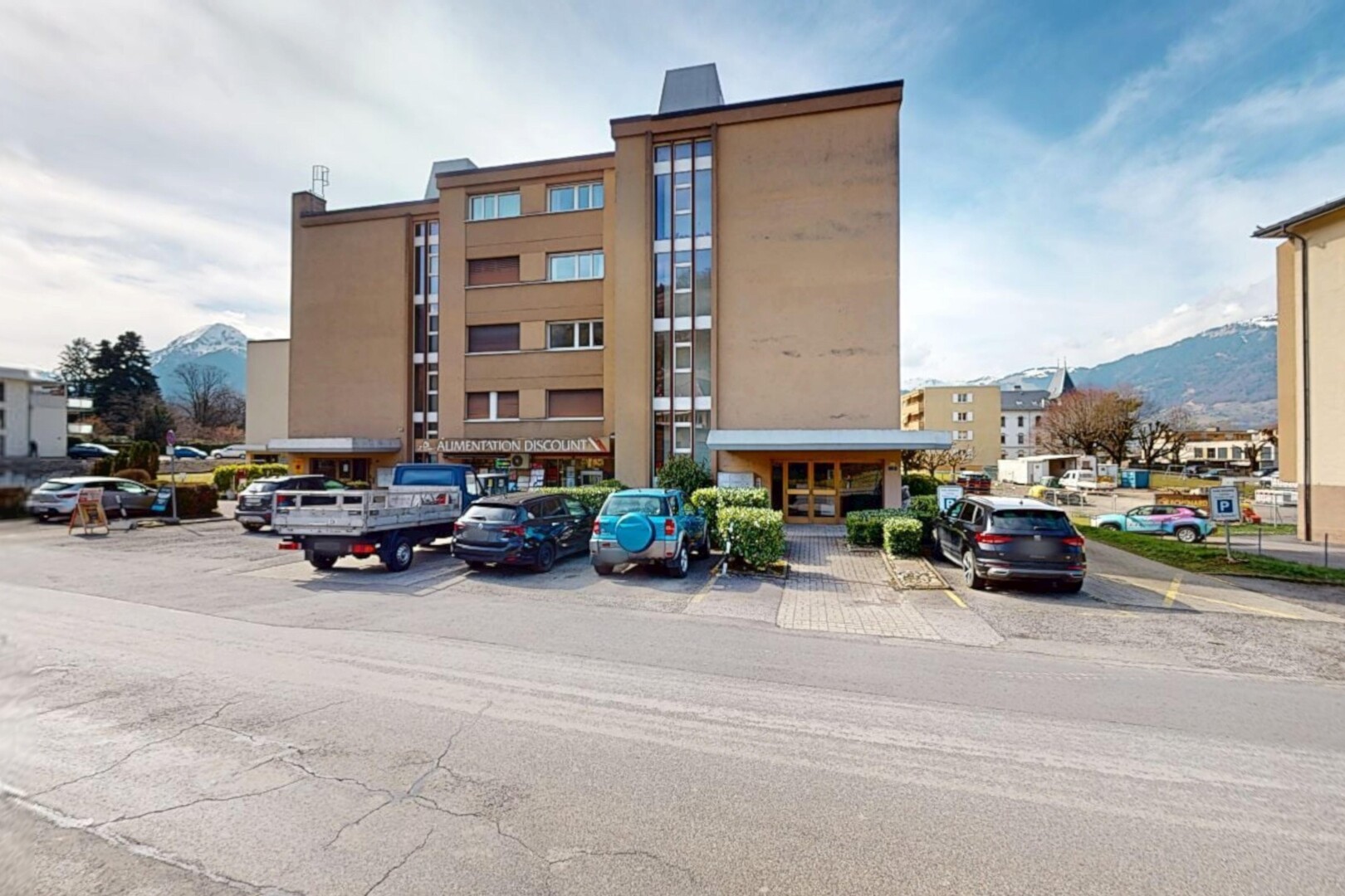 extérieur du bâtiment avec parking et vue sur la montagne