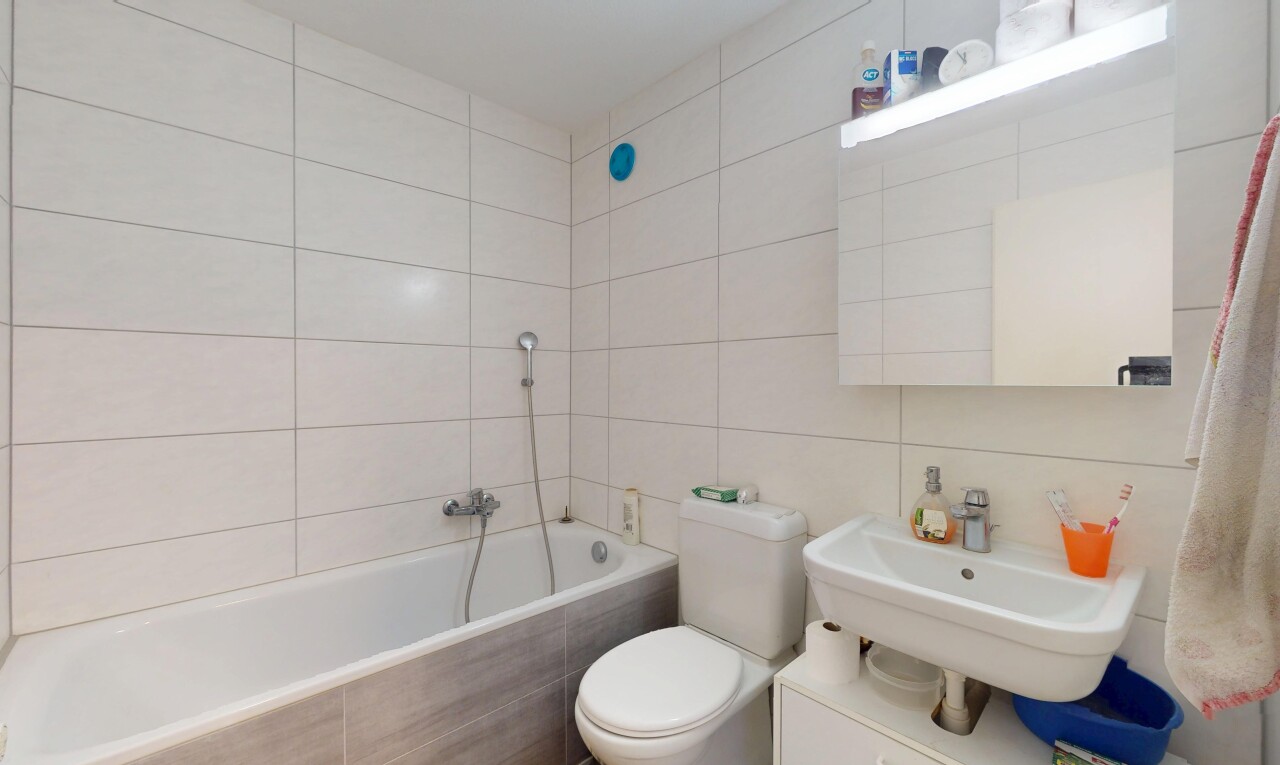 salle de bains avec évier, mur en carrelage, salle de bain complète, bain, et toilette
